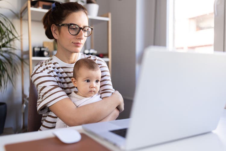 Mother holding her infant and doing her job at the modern office